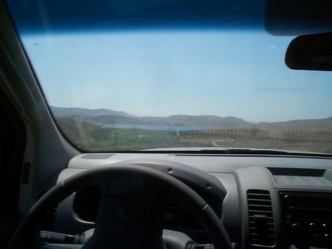 2005 Nissan Frontier - View from the driver's seat shows a steering wheel, dashboard, and a scenic landscape with a lake.