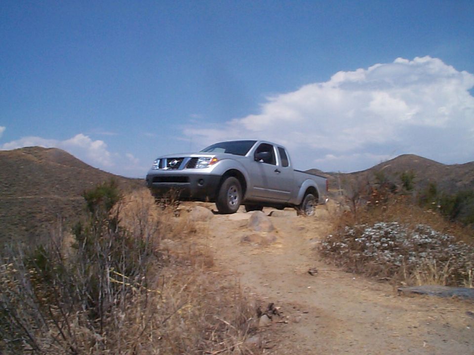 Silver 2005 Nissan Frontier pickup truck driving on a rocky dirt road