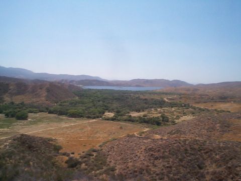 2005 Nissan Frontier - A wide view of a natural landscape hills, trees, and a body of water under a bright sky.