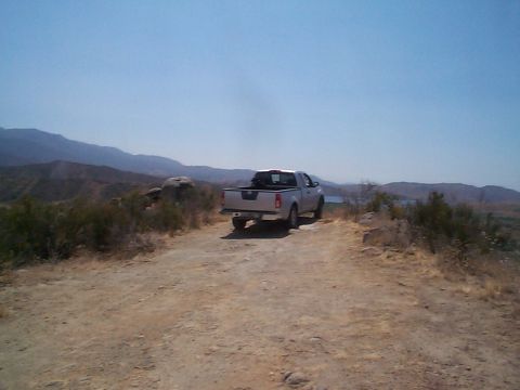 2005 Nissan Frontier - Rear view of a silver 2005 Nissan Frontier parked on a dirt road in a mountainous landscape.