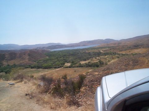 2005 Nissan Frontier - A view from a vehicle's perspective shows a vast landscape with a lake and rolling hills under a clear sky.