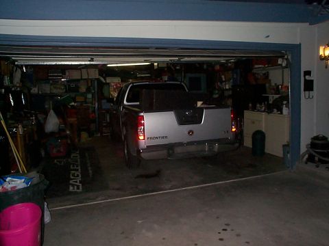 2005 Nissan Frontier - The rear of a Nissan Frontier pickup truck is visible inside a garage, with its tailgate down.