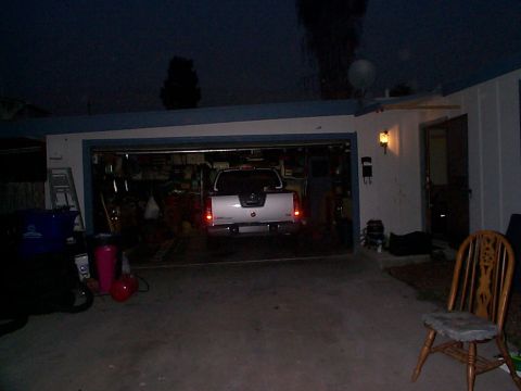 2005 Nissan Frontier - Rear view of a white 2005 Nissan Frontier pickup truck parked inside a garage at night.