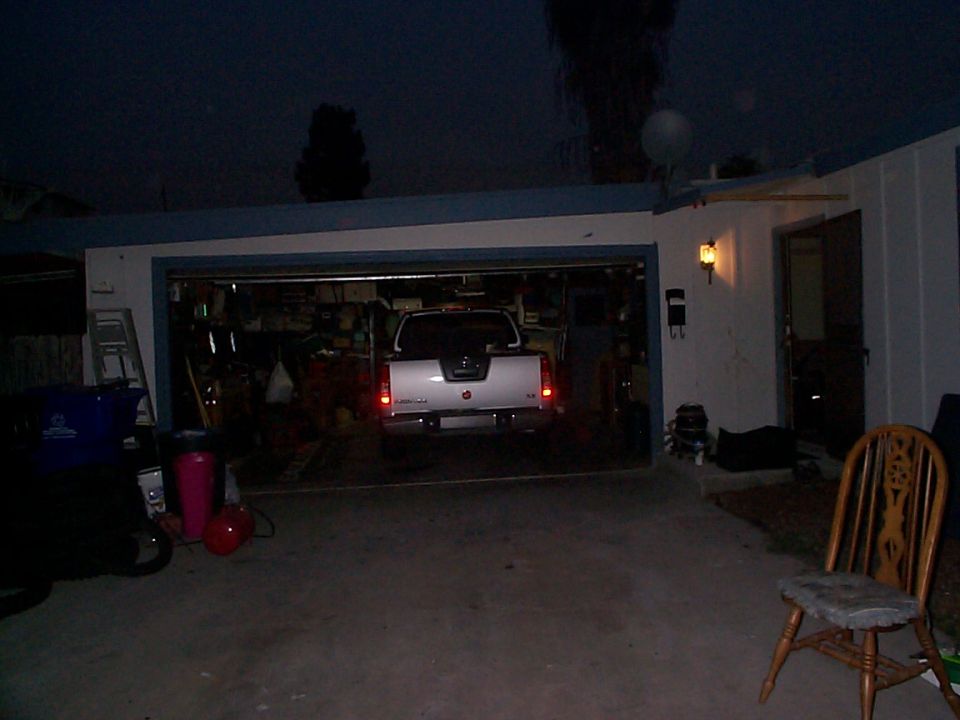 White 2005 Nissan Frontier pickup truck parked in a garage, rear view