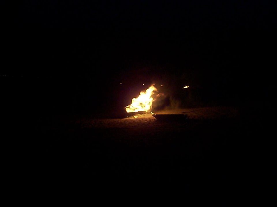 Vehicle engulfed in flames at night with "SUPERMOTORS" watermark