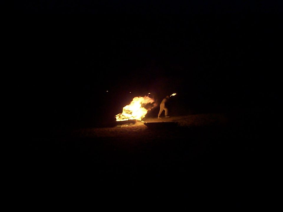 Person holding a torch near a large fire at night
