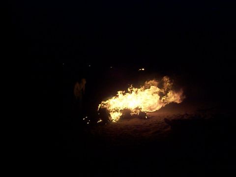 2005 Nissan Frontier - A large bonfire illuminates the dark night, with a figure visible in the background.