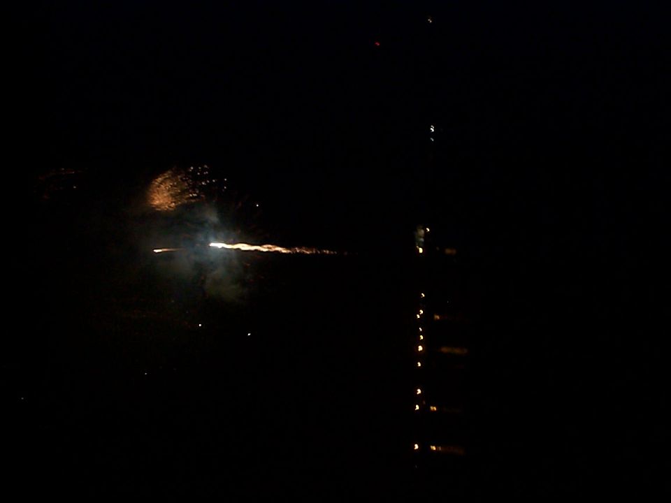 Fireworks exploding in the night sky with reflections on the water below. Supermotors.net logo visible