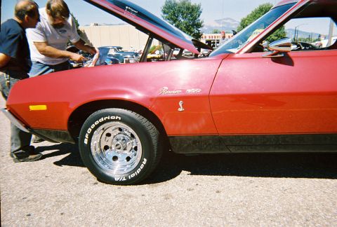 1972 Ford Ranchero - A red 1972 Ford Ranchero 500 is displayed with its hood open, revealing the engine bay and a prominent cobra emblem on the fender.