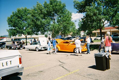 1972 Ford Ranchero - Several custom cars are on display at an outdoor event, with attendees observing them.