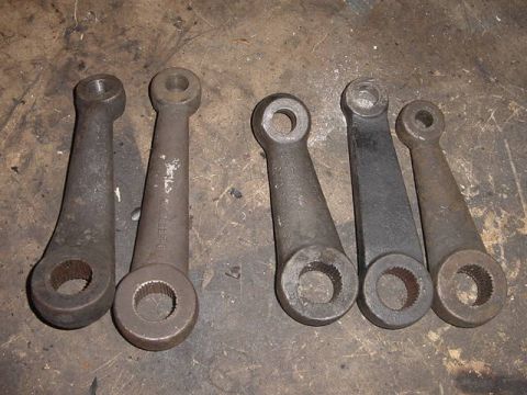 1971 Ford Bronco - Several steering arms are laid out on a surface, showing different wear and finishes.