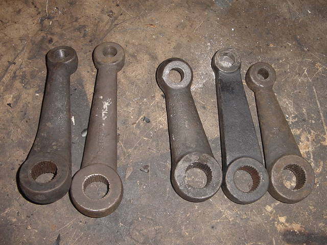 Five metal steering arms with splined holes on a workbench