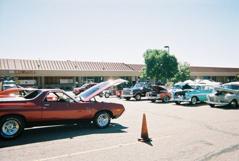 1972 Ford Ranchero - Several classic cars are parked in a lot with their hoods up, suggesting a car show or gathering.