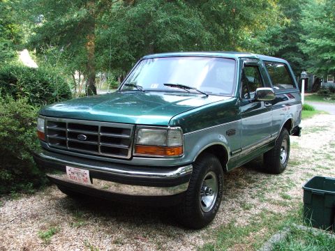 1996 Ford Bronco - This 1996 Ford Bronco is parked on a gravel surface surrounded by trees and greenery.