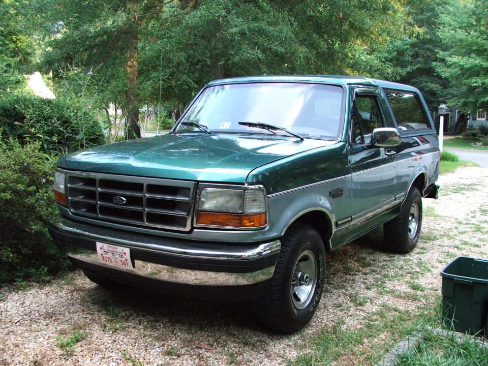 Green two-tone Ford Bronco SUV parked on gravel driveway, three-quarter front view