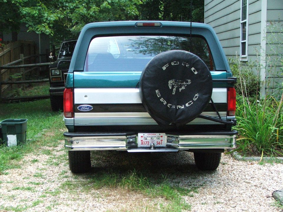 Rear view of green two-tone Ford Bronco with black Bronco-logo spare tire cover
