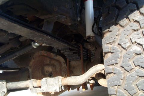 2002 Ford Excursion - Close-up view of the suspension system, showing leaf springs, a shock absorber, and part of the axle.