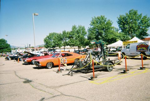 1972 Ford Ranchero - A row of cars are parked outside under a clear sky, with trees and tents in the background.