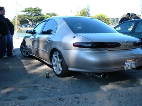 1995 Ford Taurus - A silver sedan is parked outdoors with people nearby, a lake visible in the background.