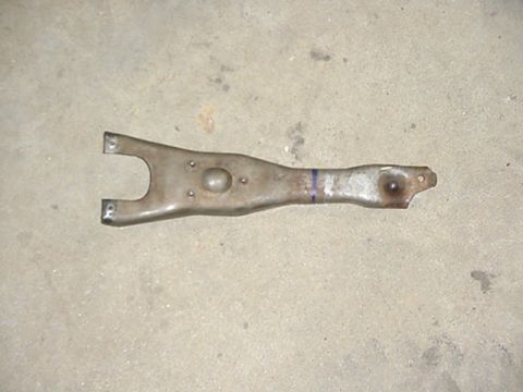 1988 Ford Bronco - A metal clutch fork is shown against a concrete background.