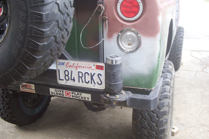 Rear bumper of a green off-road rig with California plate L84 RCKS and hockey sticker