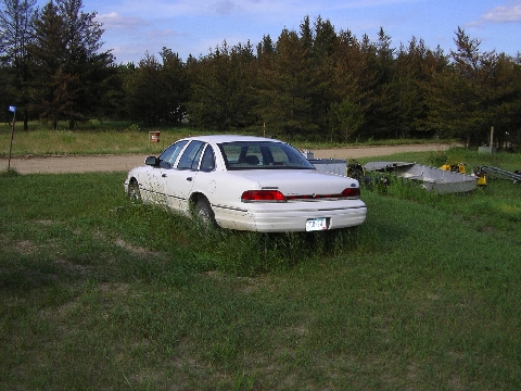 1998 Ford Crown Victoria - White 1998 Ford Crown Victoria sits in a grassy field with trees in the background.