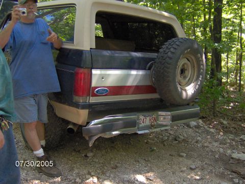 1978 Ford Bronco - A man stands next to a Ford Bronco parked on a dirt road in a wooded area.