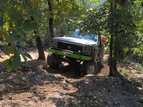 1978 Ford Bronco - Modified pickup truck with green bumper and winch navigating a dirt trail.