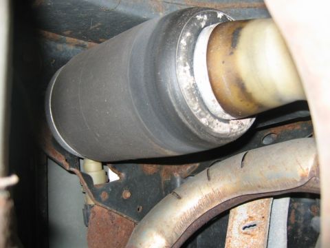 1985 Ford LTD Crown Victoria - Close-up view of a rear axle air suspension component and exhaust pipe on a vehicle.