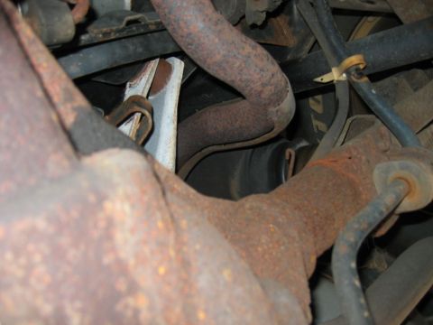 1985 Ford LTD Crown Victoria - Close-up view of heavily rusted exhaust pipes and suspension components, likely from an older vehicle.