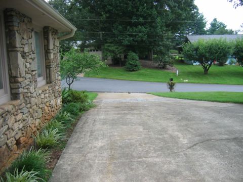1985 Ford LTD Crown Victoria - A view of a residential street with a stone-sided house and a concrete driveway.