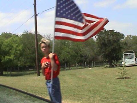 1987 Ford Bronco - A boy holds an American flag in a grassy field with a white bus in the distance.