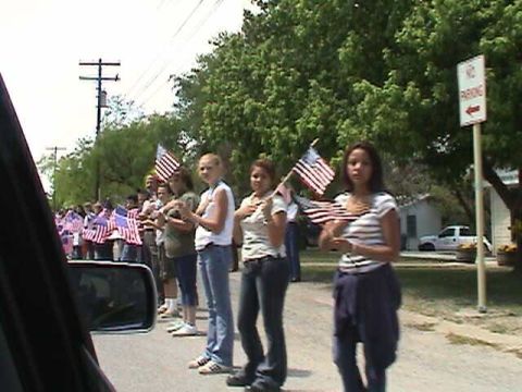 1987 Ford Bronco - A group of people are holding American flags during an outdoor event.