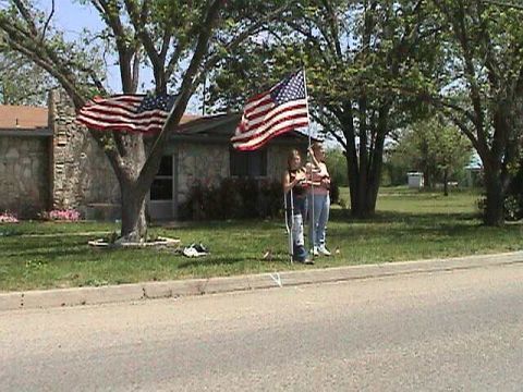 1987 Ford Bronco - Two people are holding American flags in a yard with a house in the background.