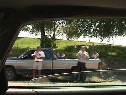 1987 Ford Bronco - Two men stand by a pickup truck adorned with small American flags on a sunny day.