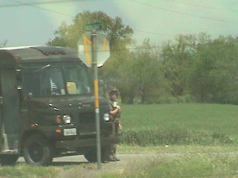 1987 Ford Bronco - A dark colored delivery truck is parked on the side of a road with a person standing nearby.