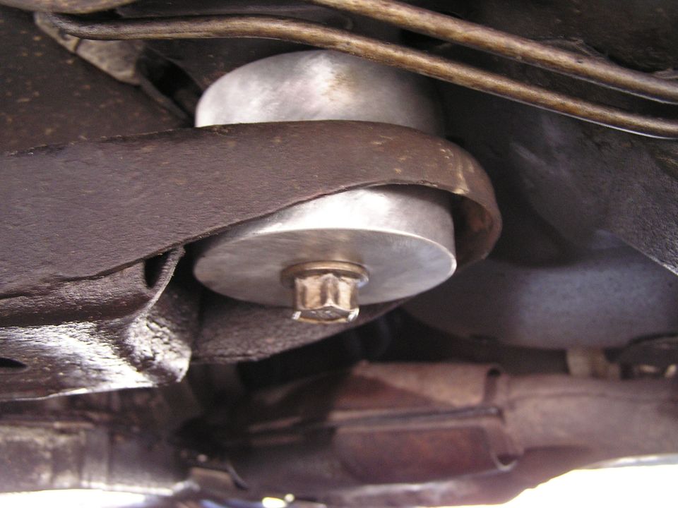 Close-up of a canister filter with hex base nut tucked among chassis brackets and steel lines