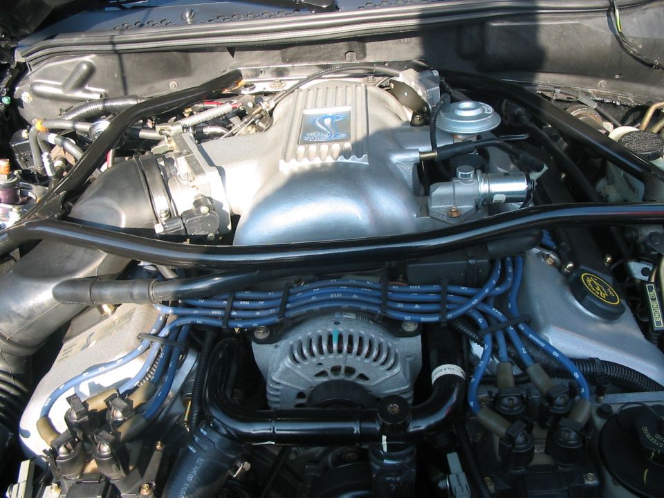 Engine bay with silver intake manifold, blue spark plug wires, and alternator