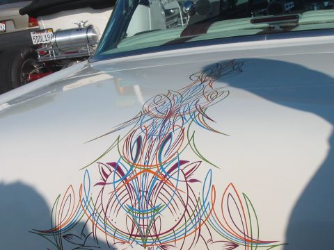 1986 Ford Bronco - Close-up of a car hood intricate pinstripe artwork, with another vehicle partially visible.