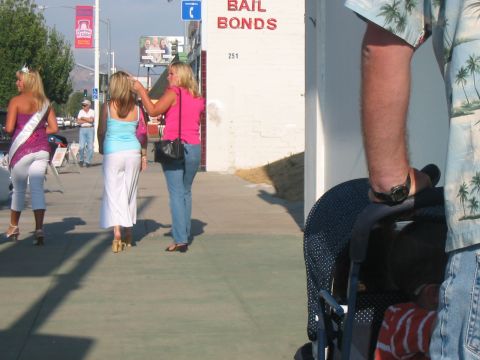 1986 Ford Bronco - People walk past a bail bonds business on a sunny day, with a stroller visible in the foreground.