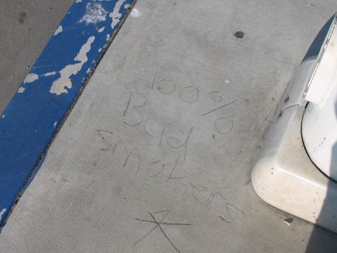 1986 Ford Bronco - Graffiti on pavement reads '100% Bud smokers', with a portion of a white vehicle visible on the right.