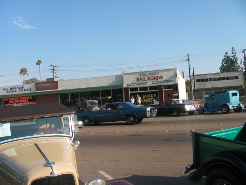 1986 Ford Bronco - Vintage vehicles are visible on a street with a bail bonds business in the background.