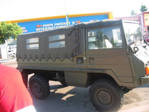 1986 Ford Bronco - Military truck with canvas top and side windows parked outdoors.