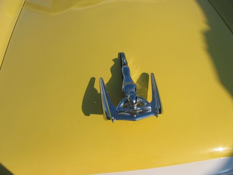 1986 Ford Bronco - A chrome hood ornament is mounted on the yellow hood of a car.