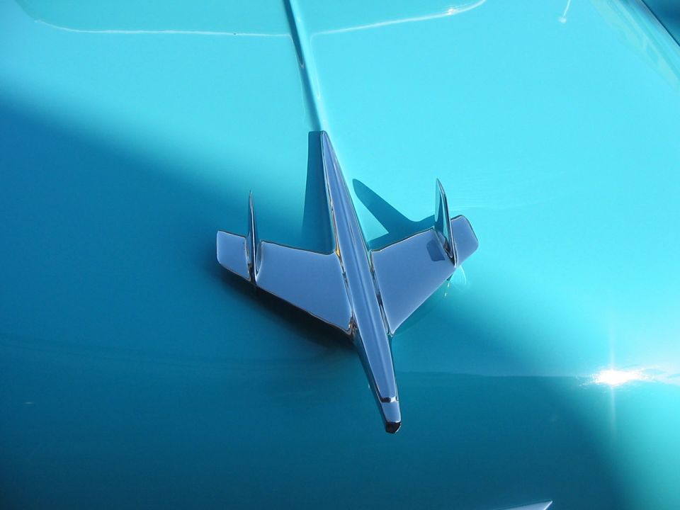 chrome airplane hood ornament on a turquoise car hood