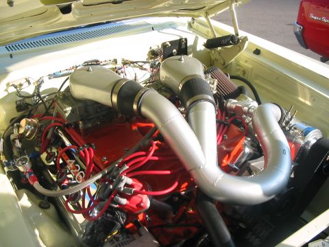 1986 Ford Bronco - Close-up of a modified engine bay, showing twin air intakes and vibrant red wiring.