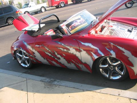 1986 Ford Bronco - Customized red convertible with flame graphics and chrome wheels is parked on the street.