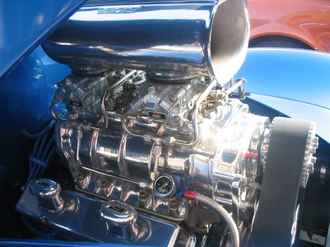 1986 Ford Bronco - Polished chrome engine components gleam under the sun, a prominent supercharger and dual carburetors.