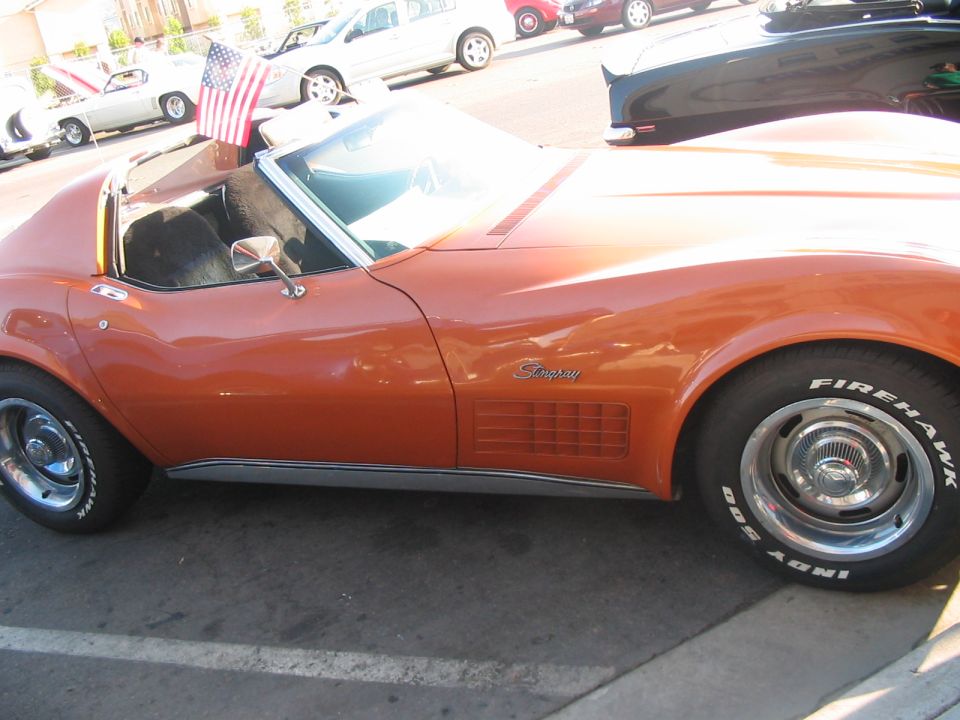 Orange convertible sports car side view with 'Stingray' emblem and Firehawk tires