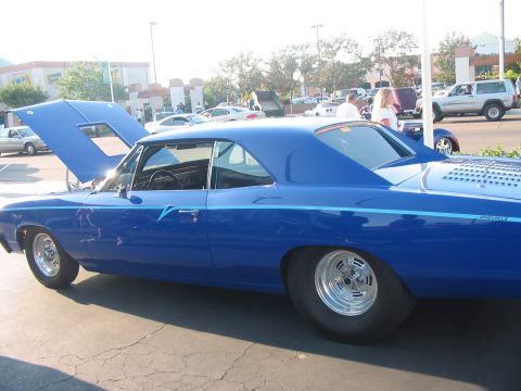 1986 Ford Bronco - A blue muscle car with its hood open and drag tires is parked outside.